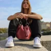 Ce sac bourse bordeaux de confection italienne est équipé d'une bandoulière en chaîne dorée garnie de cuir, à la fois réglable et amovible, ainsi qu'une large poignée. Vous pourrez le porter aussi bien à la main qu'en bandoulière, avec confort et style. Pratique et spacieux, le sac bourse dispose d'un intérieur bien organisé avec une poche simple, et se ferme aisément à l'aide d'un lien de serrage. Il est sublimé par des pièces métalliques dorées | Dovelya