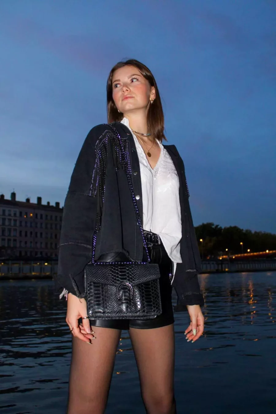Le petit sac à main fer à cheval noir en cuir est en aspect croco. Avec des petites dimensions, ce sac est chic et élégant. Ce petit sac à main fer à cheval se ferme aisément grâce à un rabat et un fermoir aimanté aux finitions en métal pour plus de sécurité. L'intérieur possède un compartiment muni d'une poche latérale zippée et d'une poche simple. Pour encore plus de praticité, il dispose d'une poche zippée à l'extérieur. Le modèle est équipé d'une bandoulière réglable en chaîne métallisée. Fabriqué en Italie | Dovelya